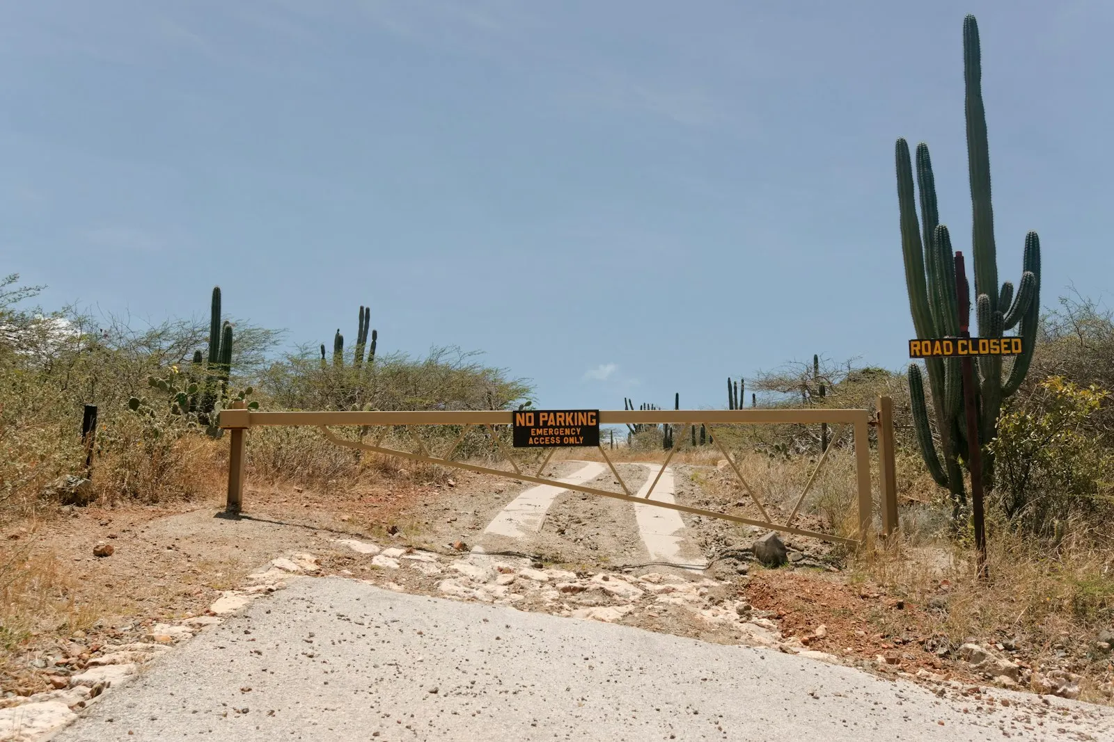 a dirt road with a gate and a sign on it