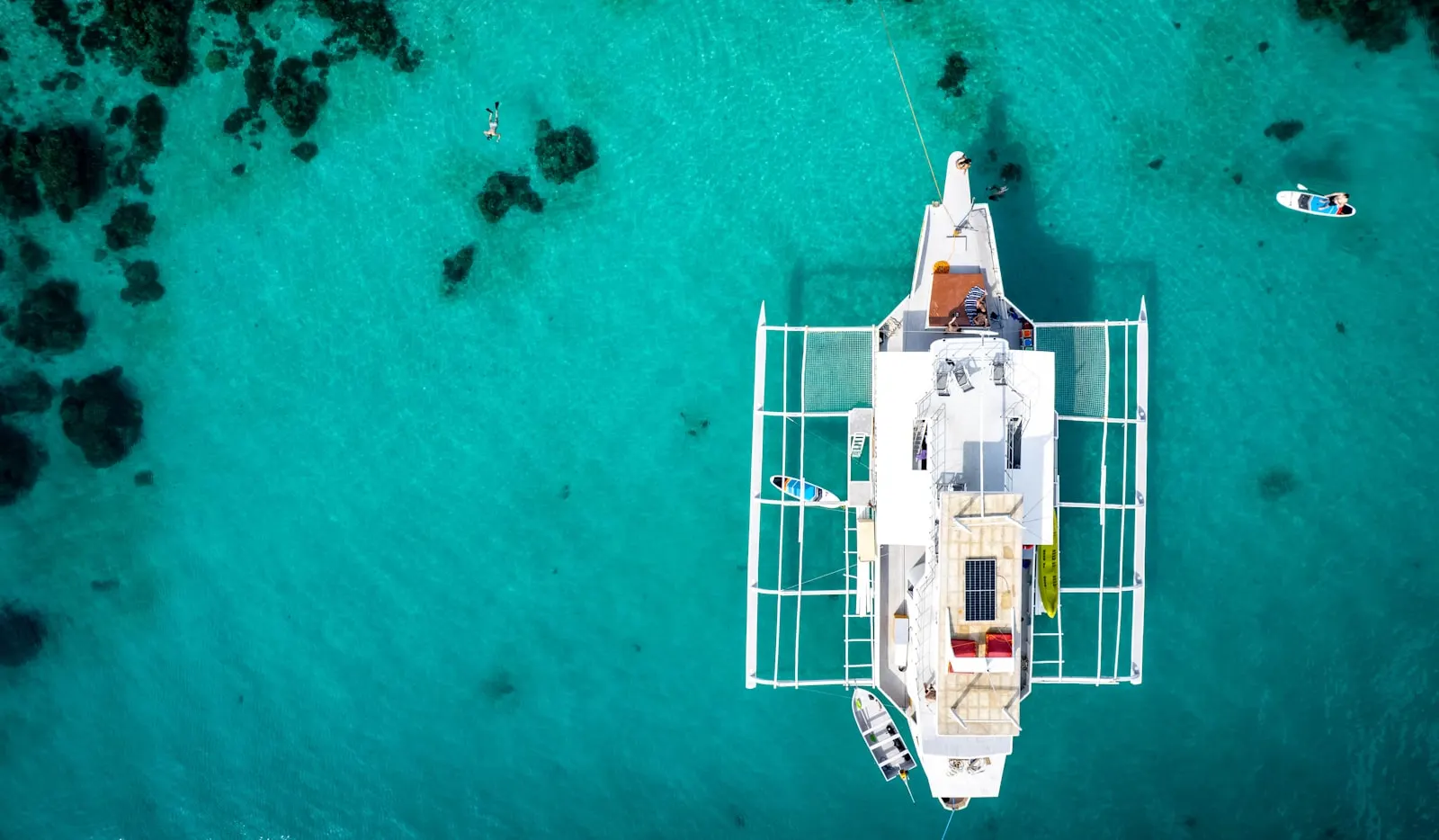 White catamaran boat floating on clear turquoise water.